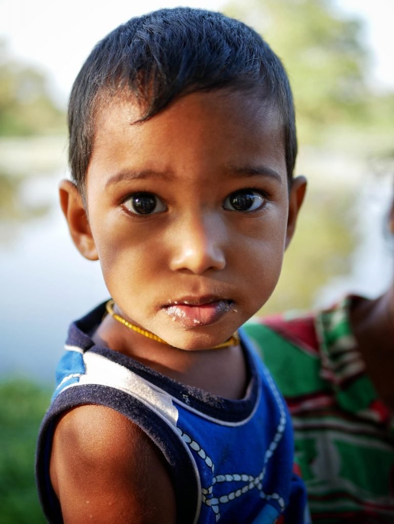 A Sri Lankean boy on the arm of her mother looking into the camera