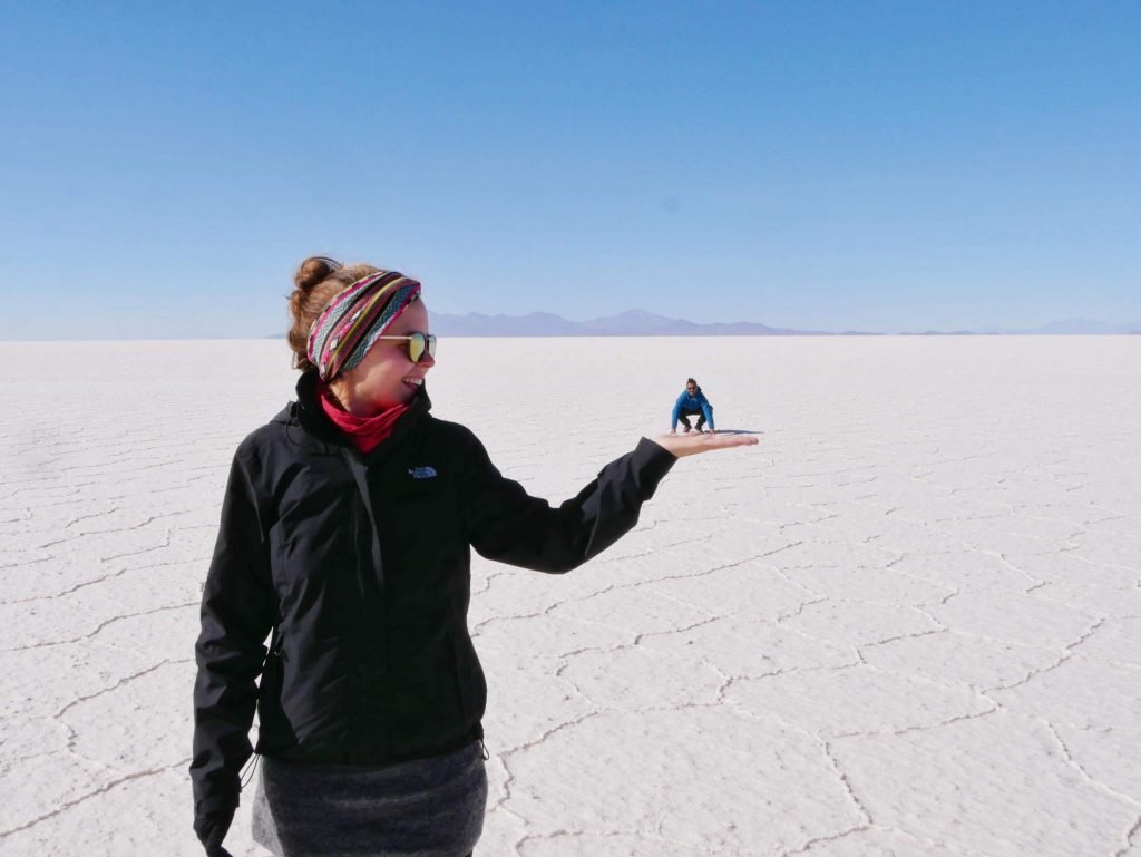 Jamin Mahmood standing in the hand of Britta Wiebe in uyuni salt flats, Bolivia