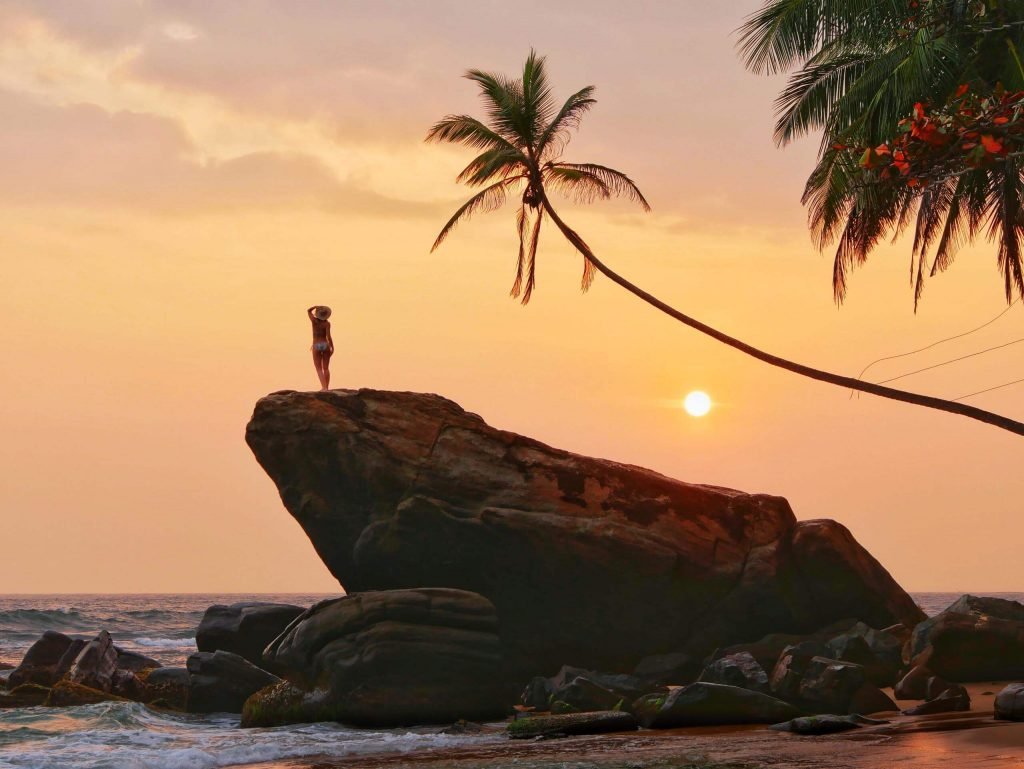 Girl standing on rock during sunset at Dalawella Beach, Unawatuna, Sri Lanka