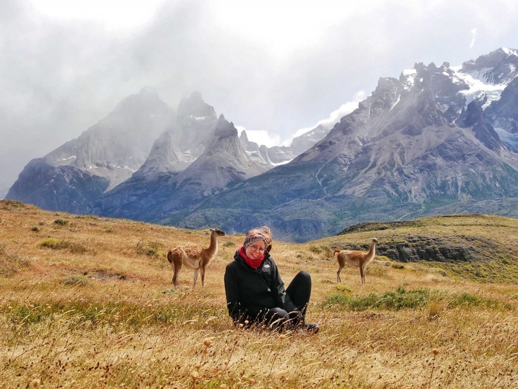 girl sitting in gras in Patagonia with llamas
