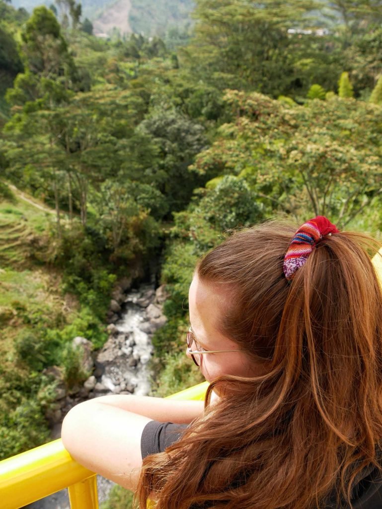girl looking in to the colombian jungle on a yellow bridge in Jardin