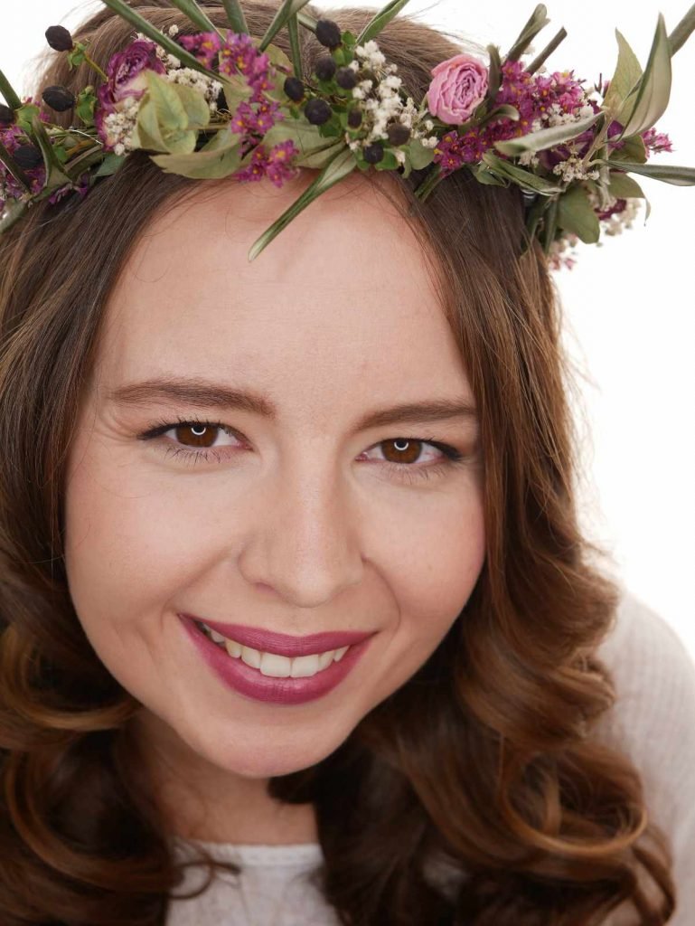 girl with make up smiling into the camera with white background with flower diadem